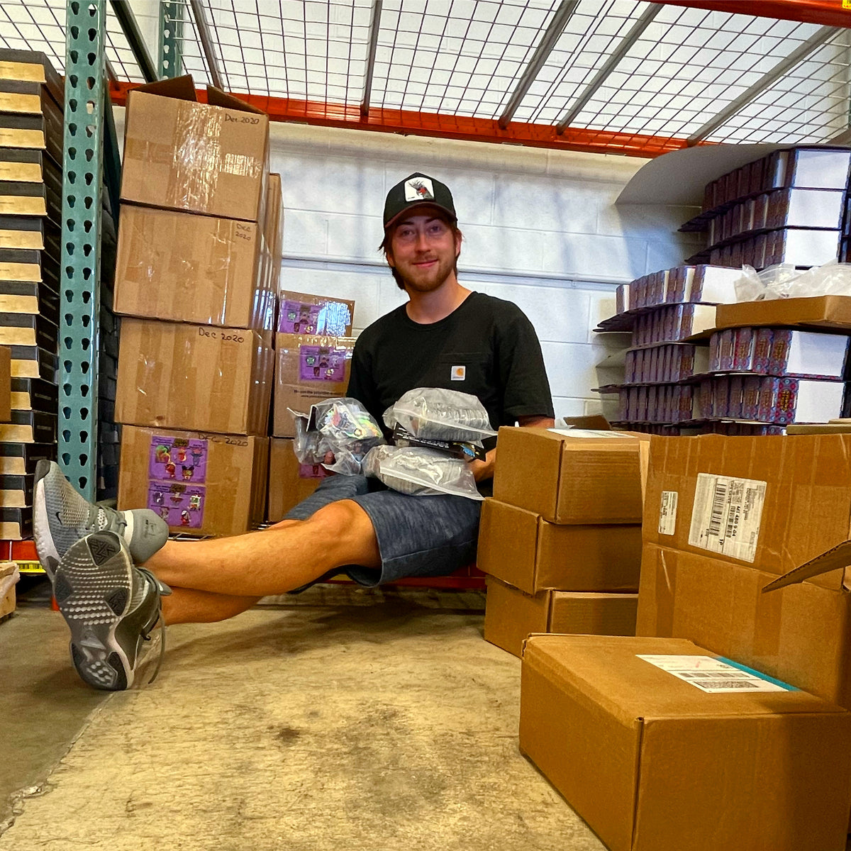 the owner holding bundles of leftover stickers in the warehouse area.